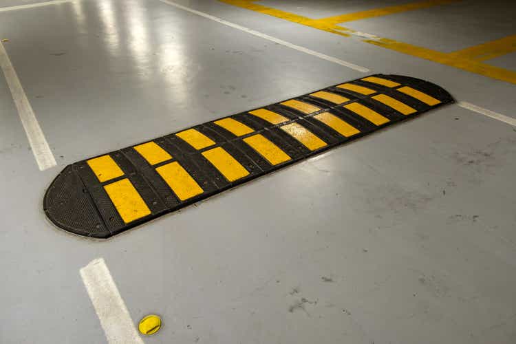 Striped black and yellow speed bump on a road.
