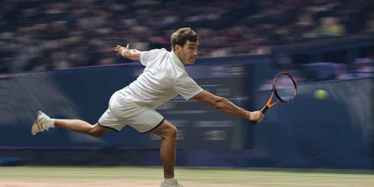 Professional Male Tennis Player In Mid Motion On Grass Court