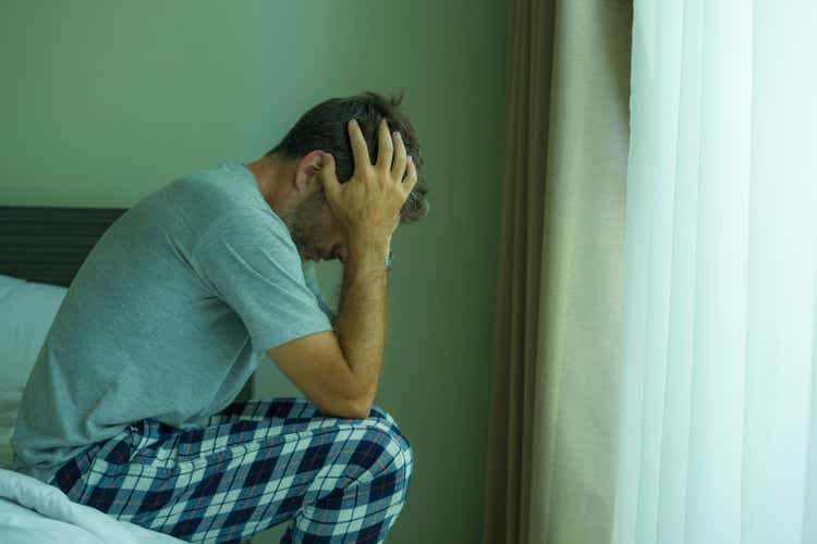 dramatic portrait of attractive scared and depressed 40s man on bed in pajamas feeling worried suffering anxiety and depression problem during virus quarantine home lockdown