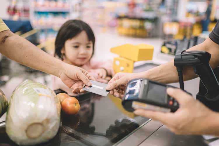 een Aziatische Chinese hogere volwassene die voor zijn het winkelen punten aan kassier bij telleruitcheckt in supermarkt betaalt