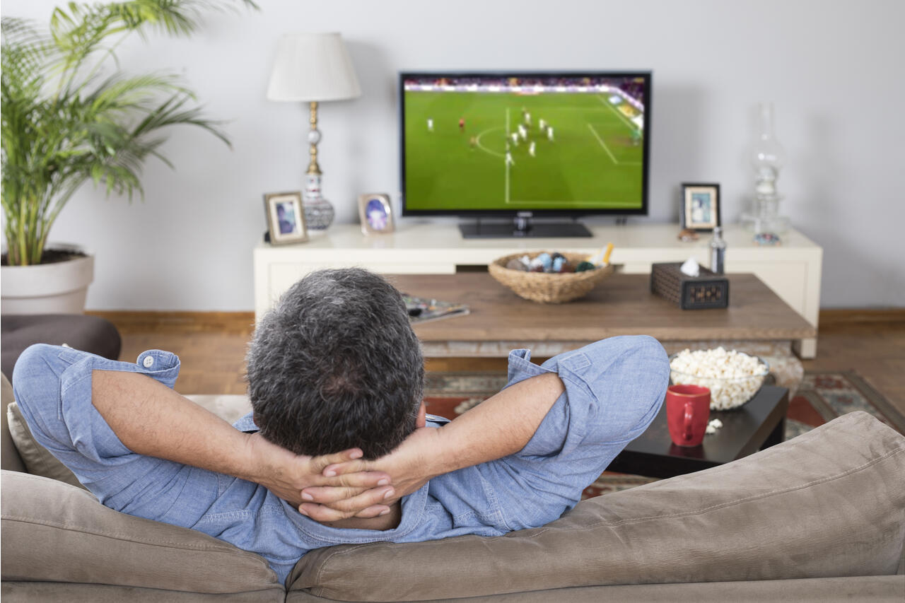 izzetugutmen/iStock via Getty Images. man watching football match at home. 