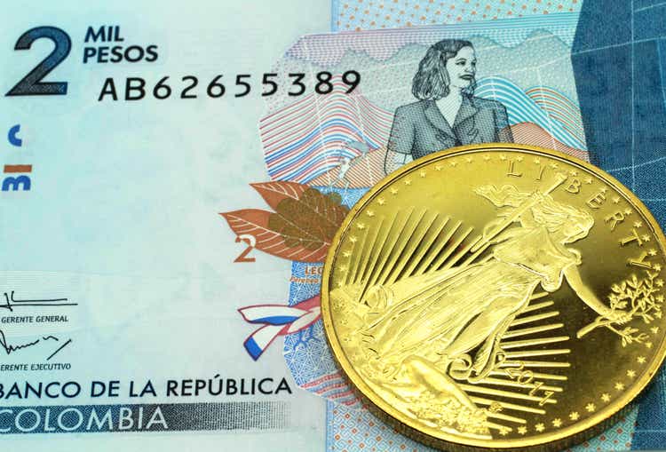 A blue two thousand Colombian peso banknote with a gold coin in macro