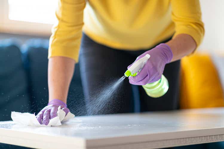 Hands in gloves disinfecting coffee table