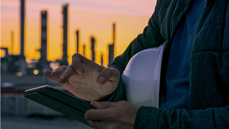 Close-up of engineer using tablet near oil refinery.