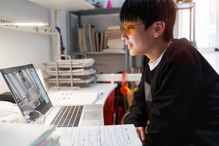 Asian kid learning from home on laptop in his bedroom
