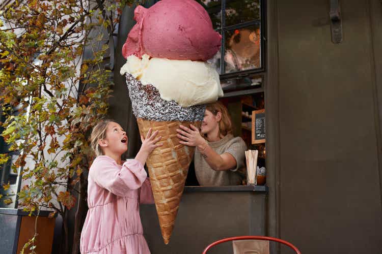 Girl buying large ice cream from take out counter of cafe