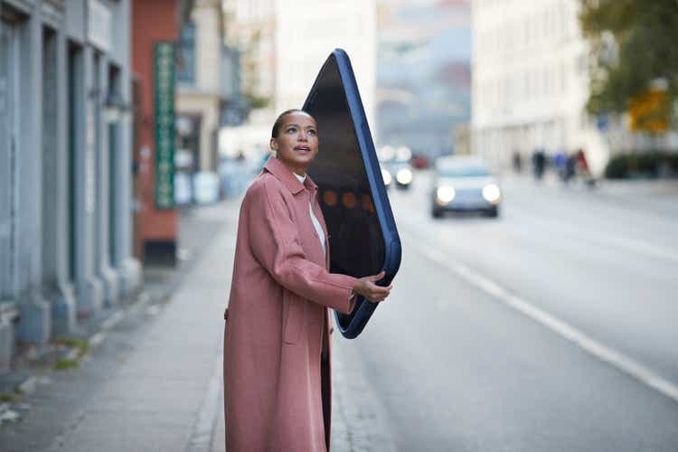 Woman talking on large mobile phone on sidewalk in city