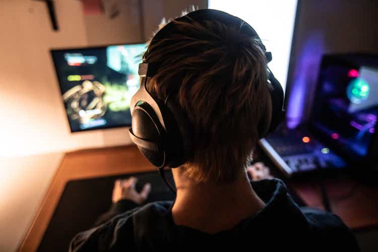Vue arrière du joueur avec casque sur jouer à des jeux vidéo en ligne dans la chambre noire - Photos