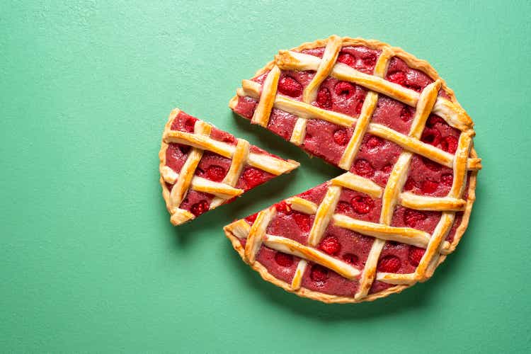 Sliced raspberry tart top view on a green background.