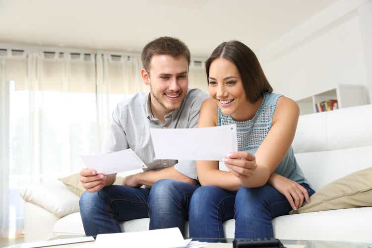 Happy couple looking and checking bills at home