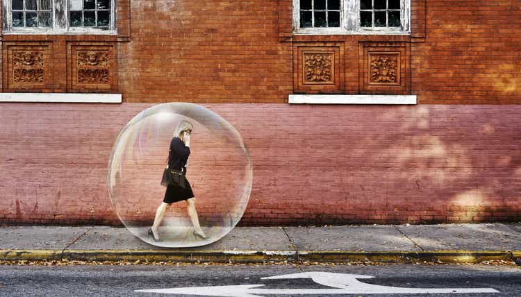 Businesswoman in a bubble walking on sidewalk.