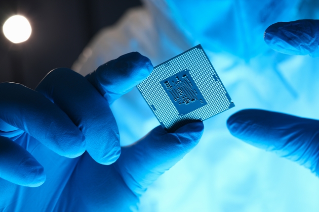 Hands in gloves hold chip testing microelectronics