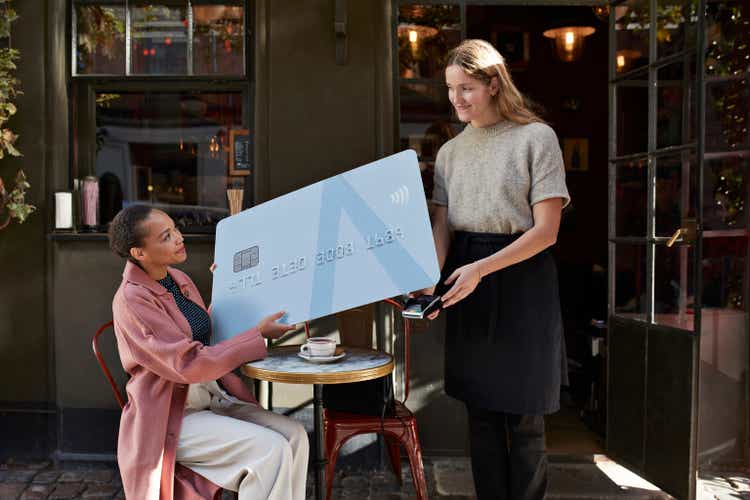 Woman paying to barista through large credit card at sidewalk café