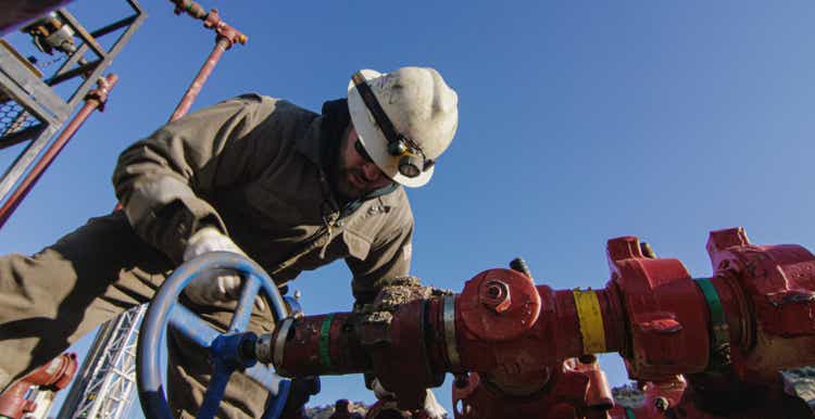 An Oilfield Worker in His Thirties Pumps Down Lines at an Oil and Gas Drilling Pad Site on a Cold, Sunny, Winter Morning