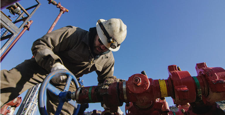 Нефтяной рабочий в тридцатые годы насосы вниз линий на нефть и газ буровой площадке сайта на холодном, солнечном, зимнее утро