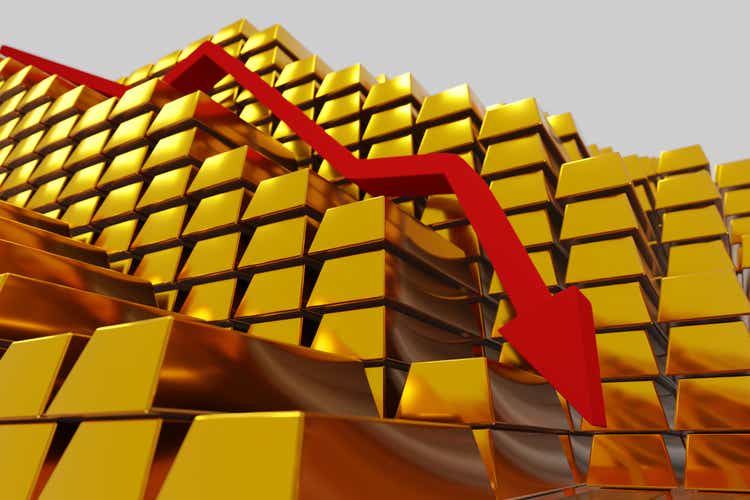 Gold prices fall in a bearish market.  Red arrow down over gold bars.  Concept digital 3D render.