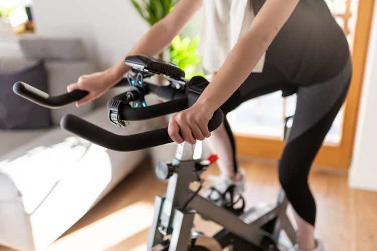 Low section of woman training on exercise bike at home