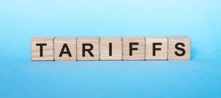 Word tariffs in letters on cube dices on blue table.