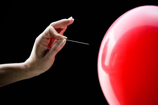 Woman"s hand about to pop balloon