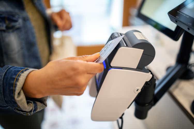 Woman using credit card for contactless payment at checkout