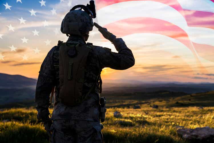 Silhouette Of A Solider Saluting Against US Flag at Sunrise
