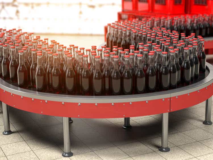 Production of soda bverages or cola. A row of bottles on conveyor belt in factory.