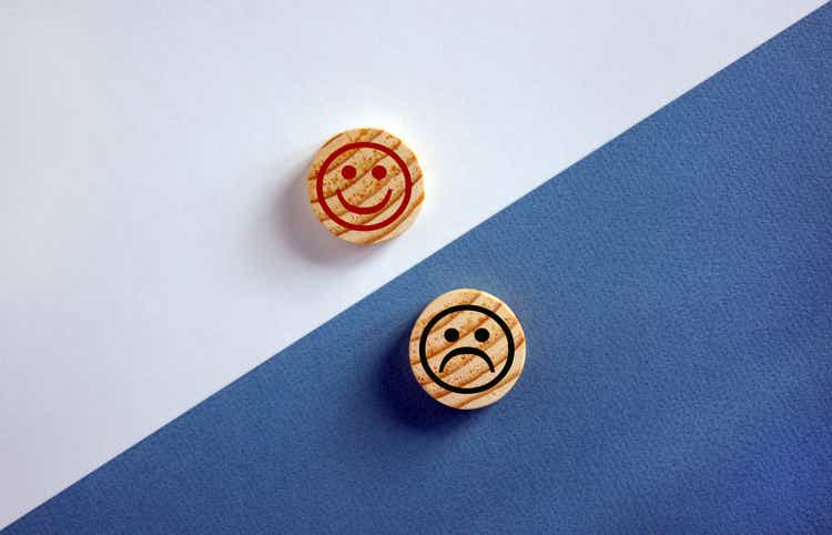 Das Konzept der Gegensätze, Holzkreise mit Lächeln auf blauem und weißem Hintergrund, flach liegen, Kopierraum.