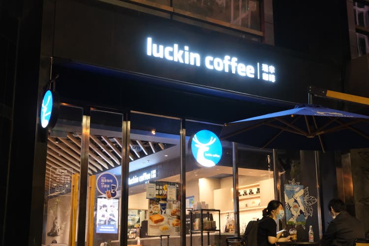 Luckin coffee shop at night with customers sitting outside