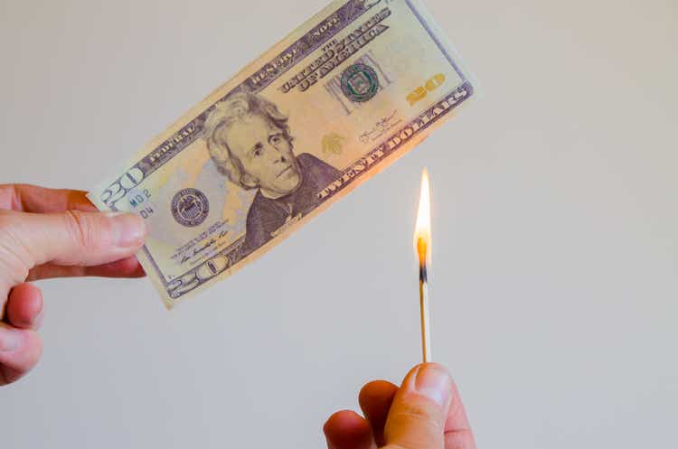 20 US dollar bill being lit by match flame