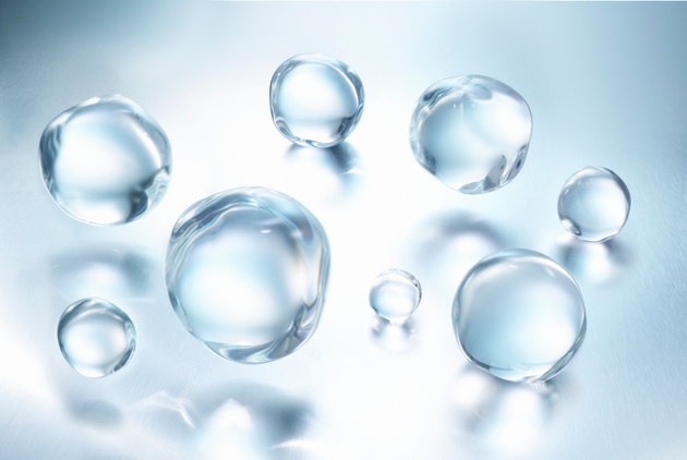 A group of large clear water droplets against blue metallic surface with reflections, close up view in a 45 degree angle