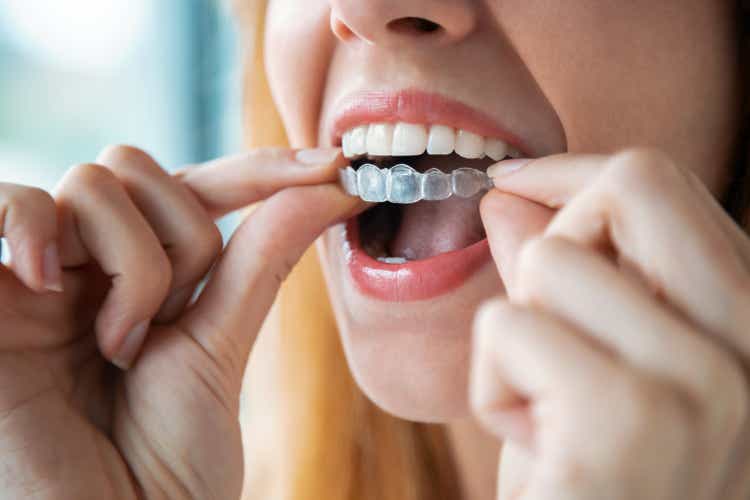 Woman wearing orthodontic silicone trainer. Invisible braces aligner.