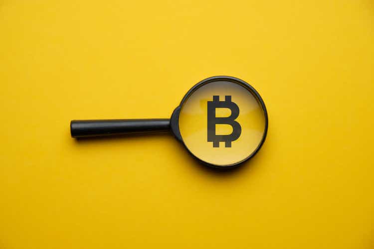 Bitcoin cryptocurrency search concept with magnifying glass on a yellow background.