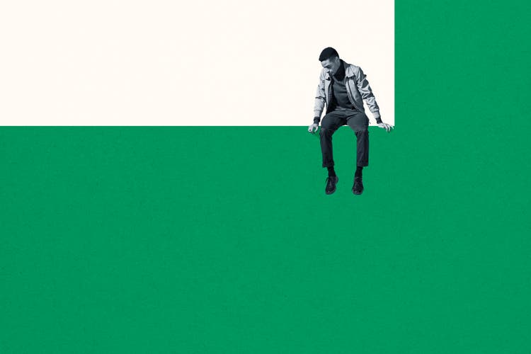 Dejected man sitting on wall while looking down