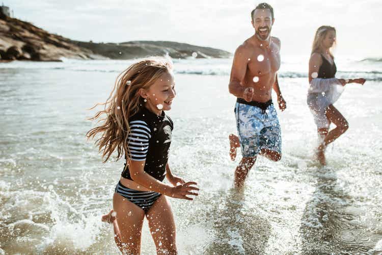 Family running and splashing on the beach