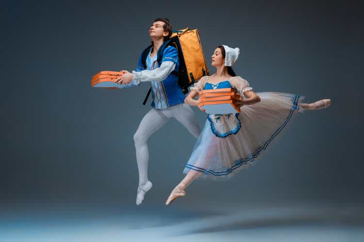 Young and graceful ballet dancers as Cinderella fairytail characters hurrying up with pizza like deliveryman