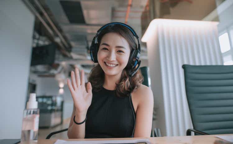 an asian chinese beautiful woman white collar worker talking to the camera video calling video conference with his business partners with face mask