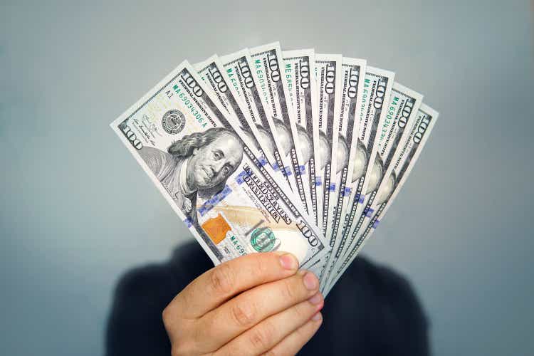 1000 dollars in 100 bills in a man"s hand close-up on a dark background. Hands holding dollar cash
