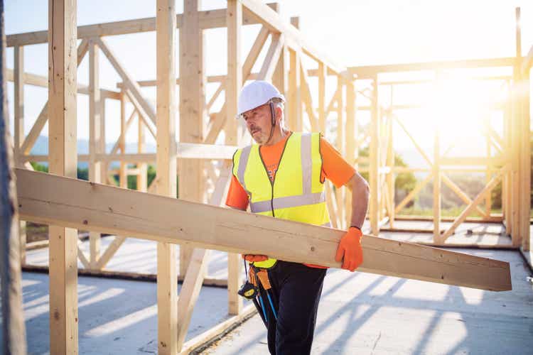 Builder Working On Wooden House