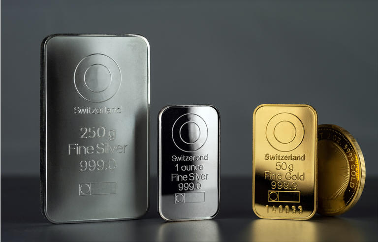 Silver and gold bars and coin on a dark