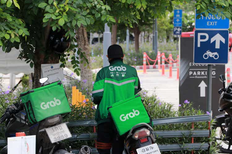 Grab bike in green corporate color of jacket and the box to put food. He is prepared to go to deliver food.