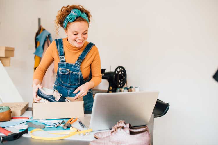 Young woman packing and selling leather shoes