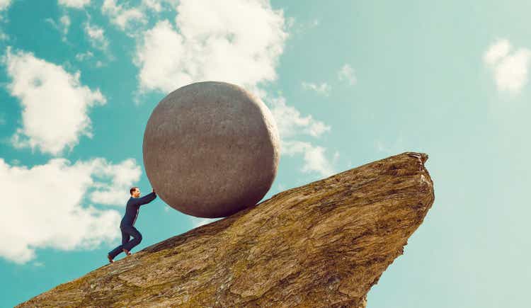 Concept of hard work for businessman pushing rock up a hill