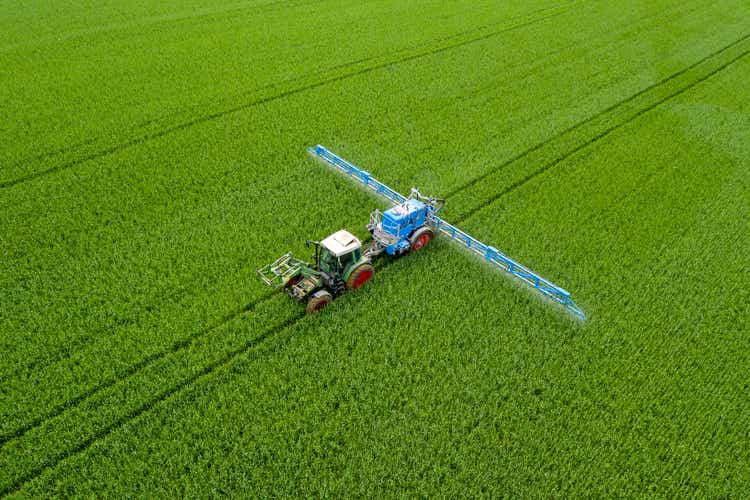 Tractor spraying wheat field, aerial view