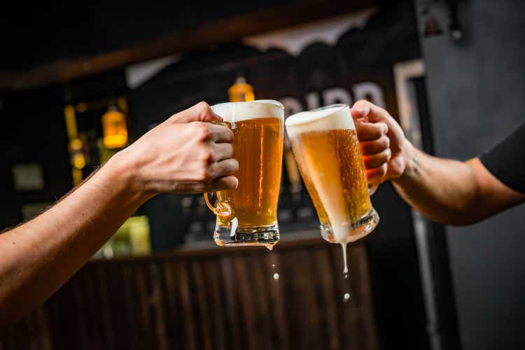 Two people toasting with mugs full of chopp.