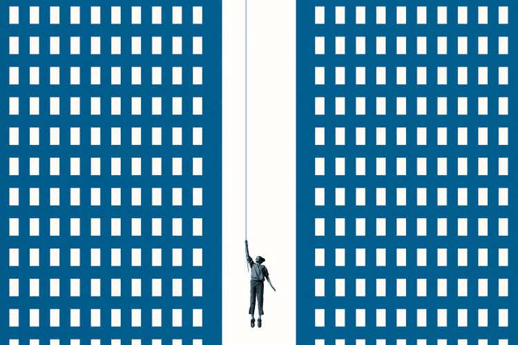 Woman hanging from rope amidst blue buildings