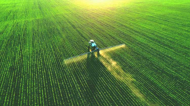 FMC Stock Soars as Company Raises Future Expectations 1 Tractor spray fertilizer on green field.