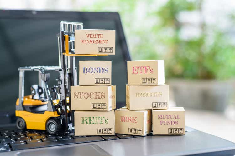 Boxes of financial products e.g REITs, bonds, commodities, communal funds, stocks, ETFs connected a laptop