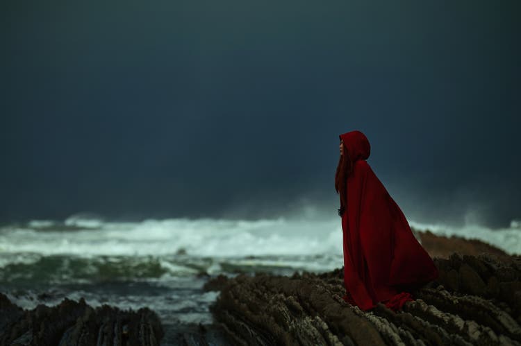 Mysterious woman wearing red on the coastline