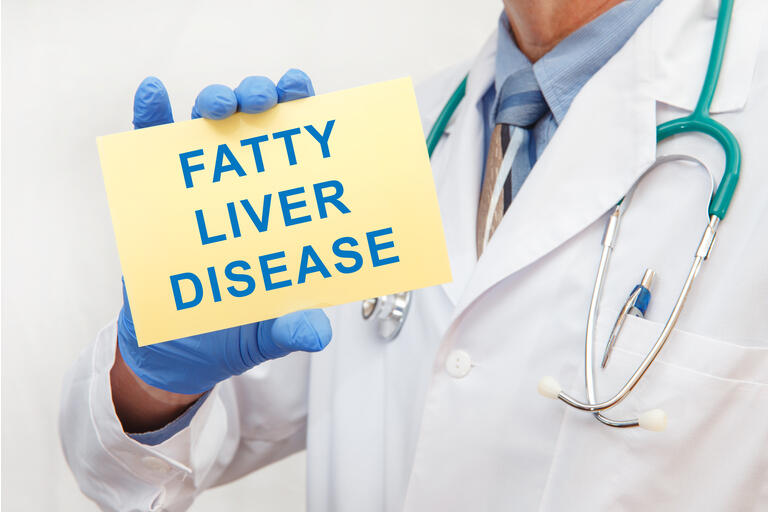 Doctor holding sign with text FATTY LIVER DISEASE closeup