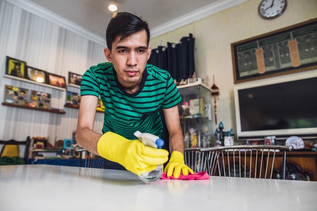 Young asian man cleaning house and wipe table using cloth